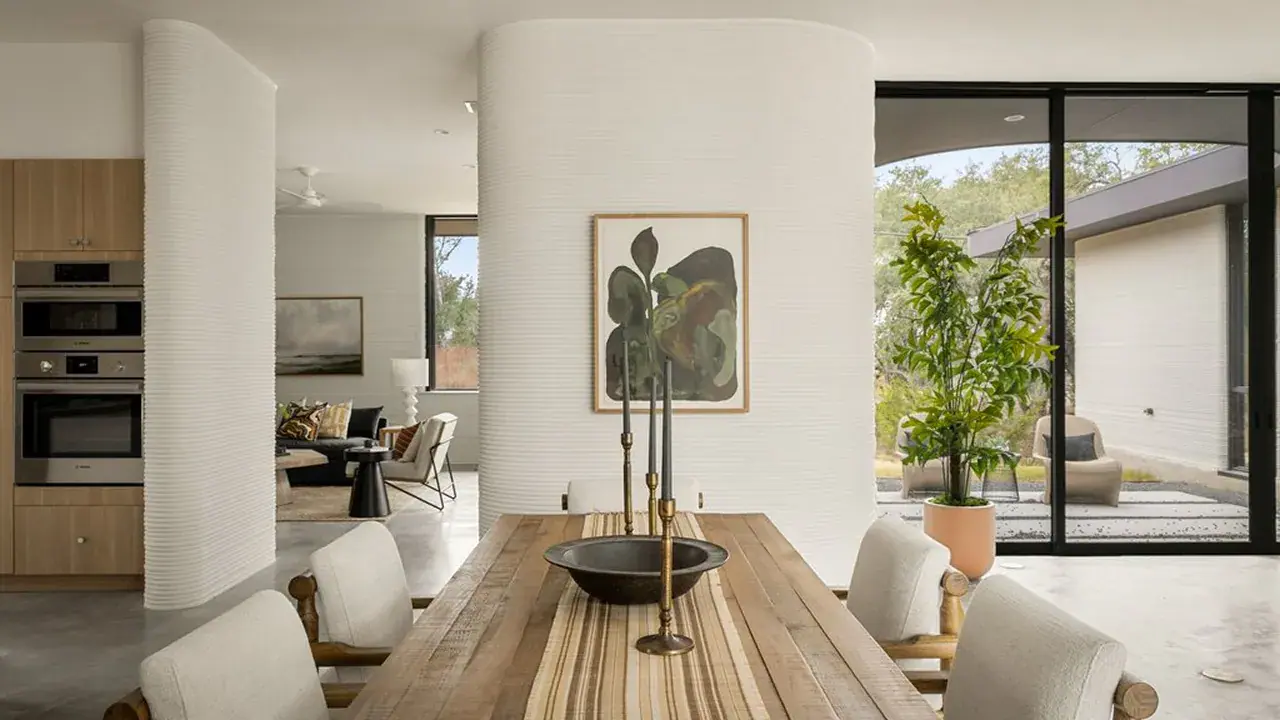 Wooden dining table with brass candlesticks, ribbed curved white interior column and glass doors
