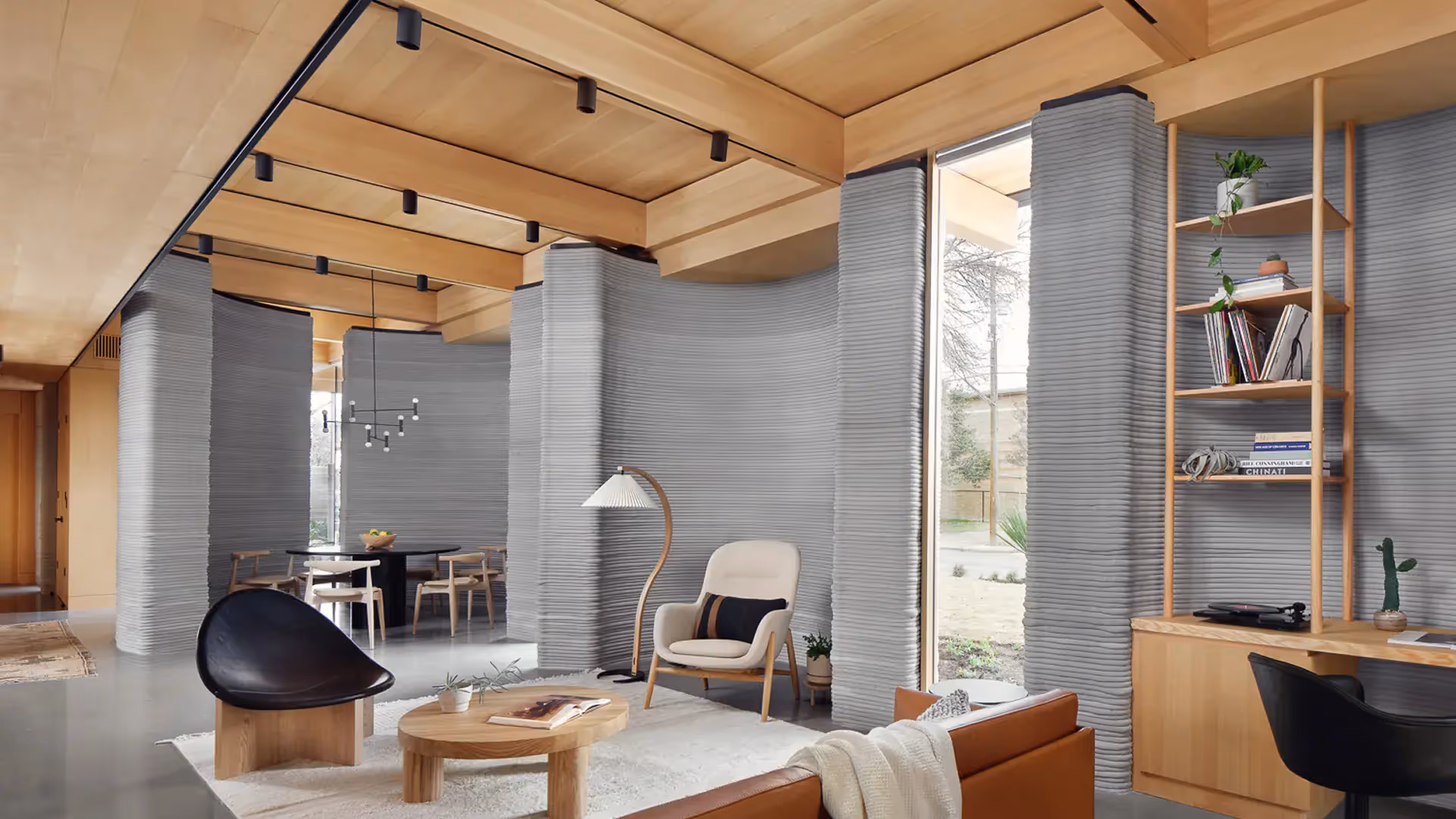 Living room with ribbed gray curved interior walls, wood ceiling beams, seating and coffee table