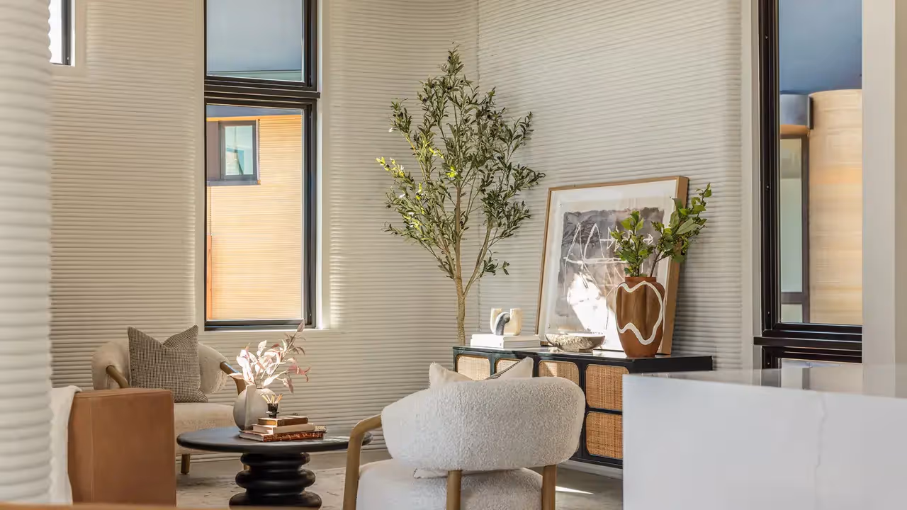 Living room with ribbed walls, lounge chairs, round coffee table, console and potted tree