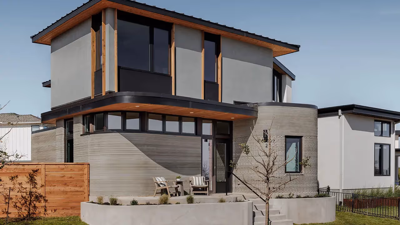 Modern two-story home with curved textured exterior, wood accents, and front patio chairs