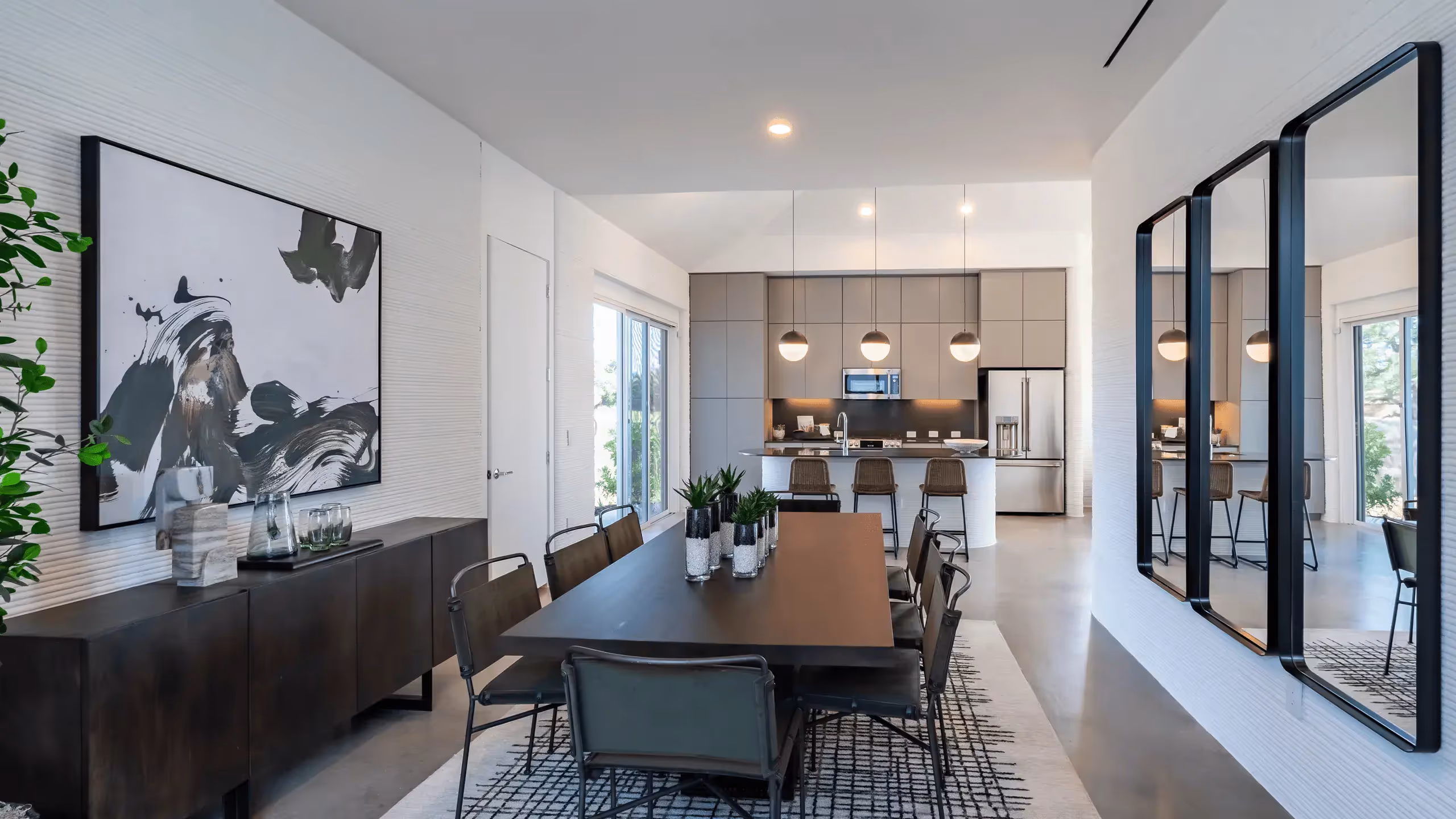 Modern dining room and open kitchen with island, pendant lights, and wall mirrors