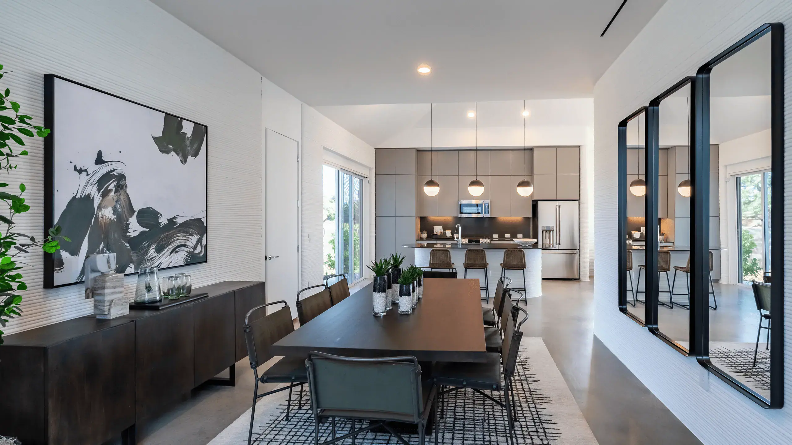 Modern dining room and open kitchen with island, pendant lights, and wall mirrors