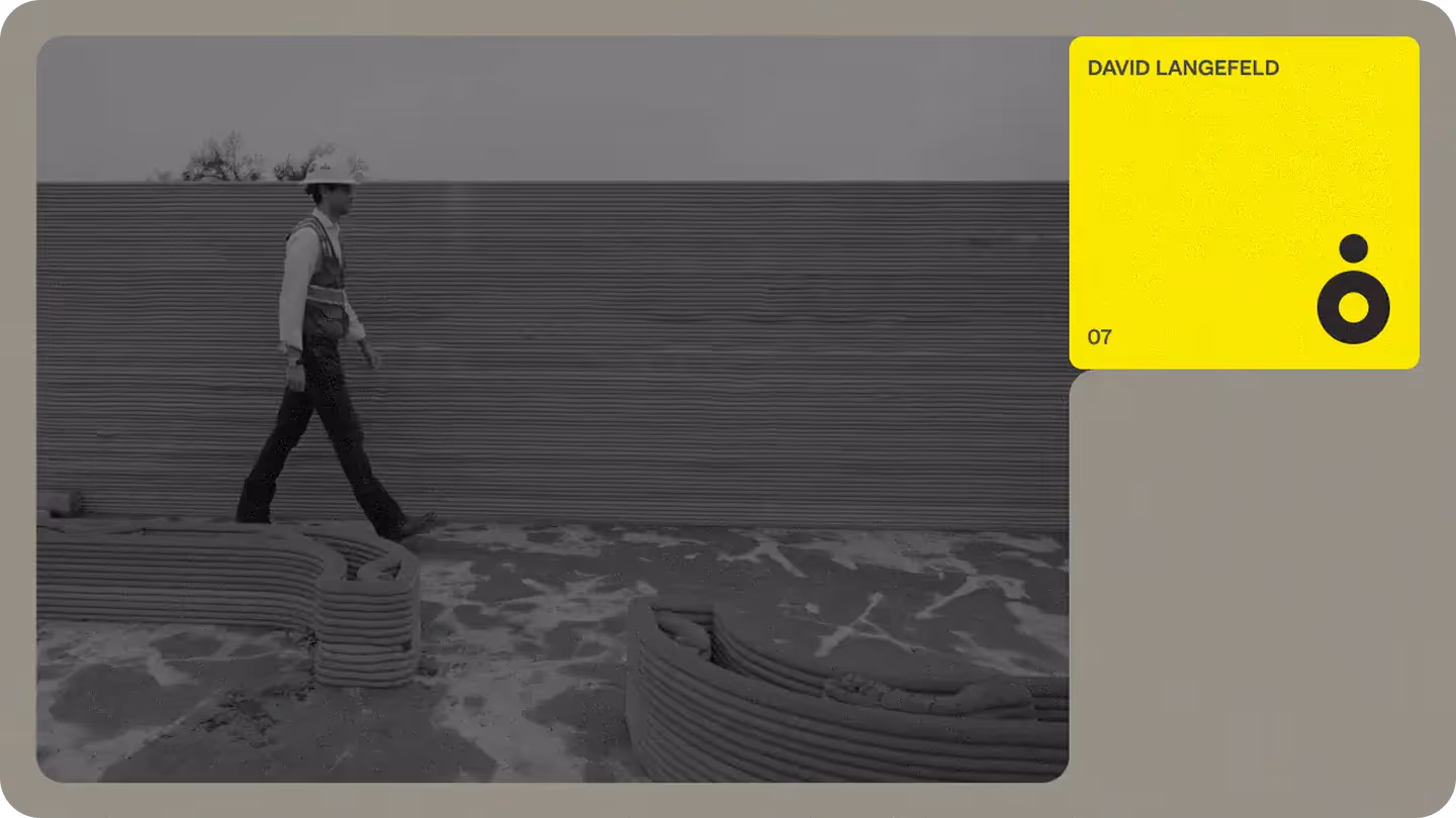 Construction worker walking past layered 3D‑printed concrete wall and stacked print beads, with yellow profile card and logo