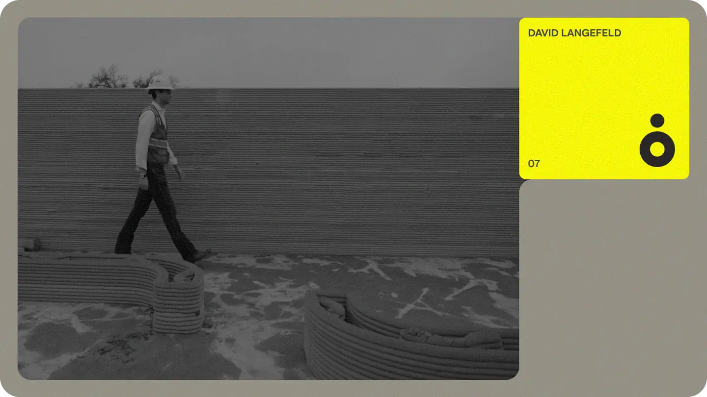 Construction worker walking past layered 3D‑printed concrete wall and stacked print beads, with yellow profile card and logo