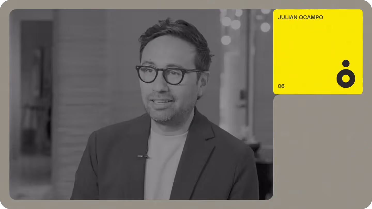 Interview portrait of a team member in glasses and blazer with a bright profile card overlay labeled "Julian Ocampo"