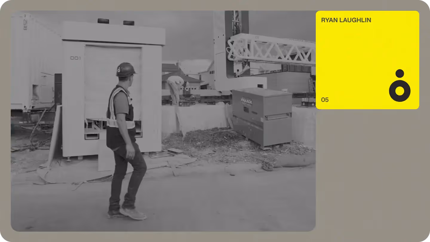 Site team member in hardhat and safety vest beside on-site 3D concrete printer and gantry, illustrating robotic construction tech