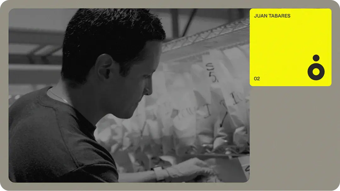 Team member inspecting labeled material bags on shelving in a fabrication workshop, showing hands-on construction tech