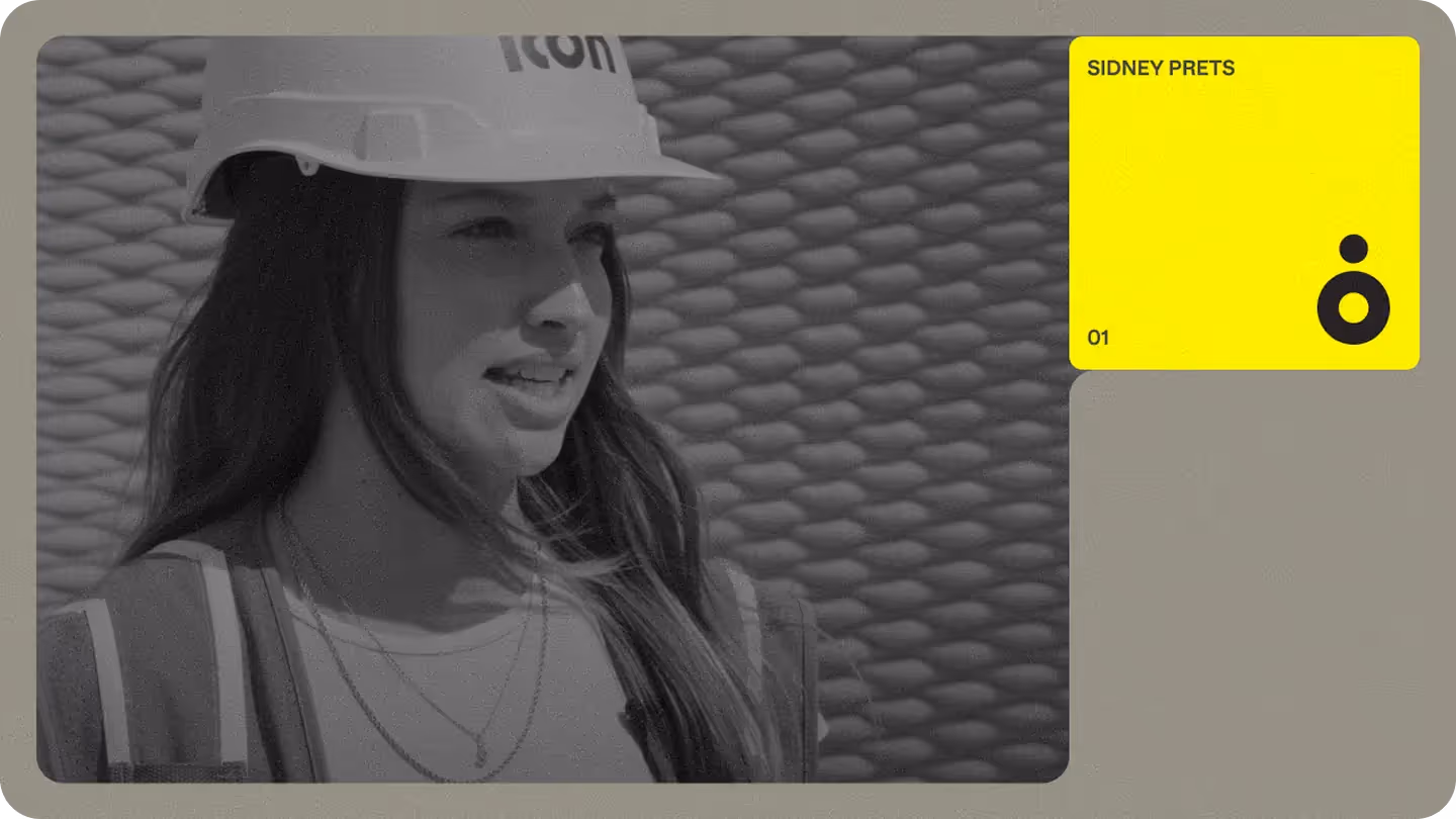 Female construction team member in hard hat and high-visibility vest speaking on site, showing Icon Build site operations.