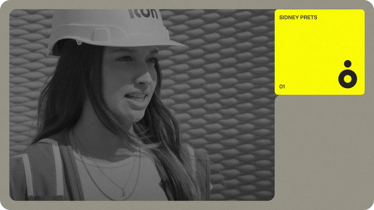 Female construction team member in hard hat and high-visibility vest speaking on site, showing Icon Build site operations.