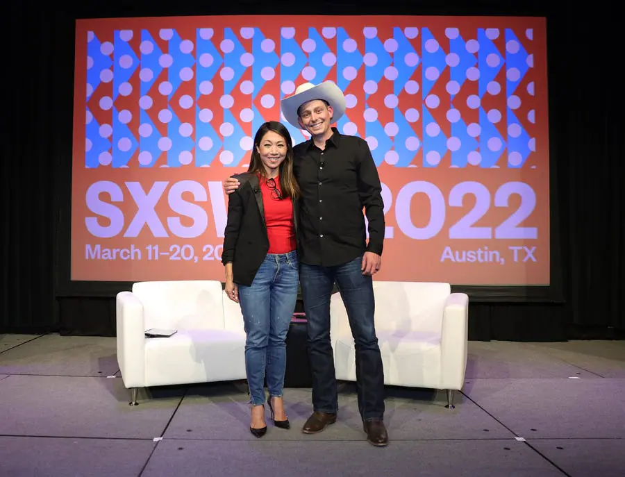 Two speakers on SXSW 2022 stage with white couches, spotlighting construction technology and 3D-printed housing innovations