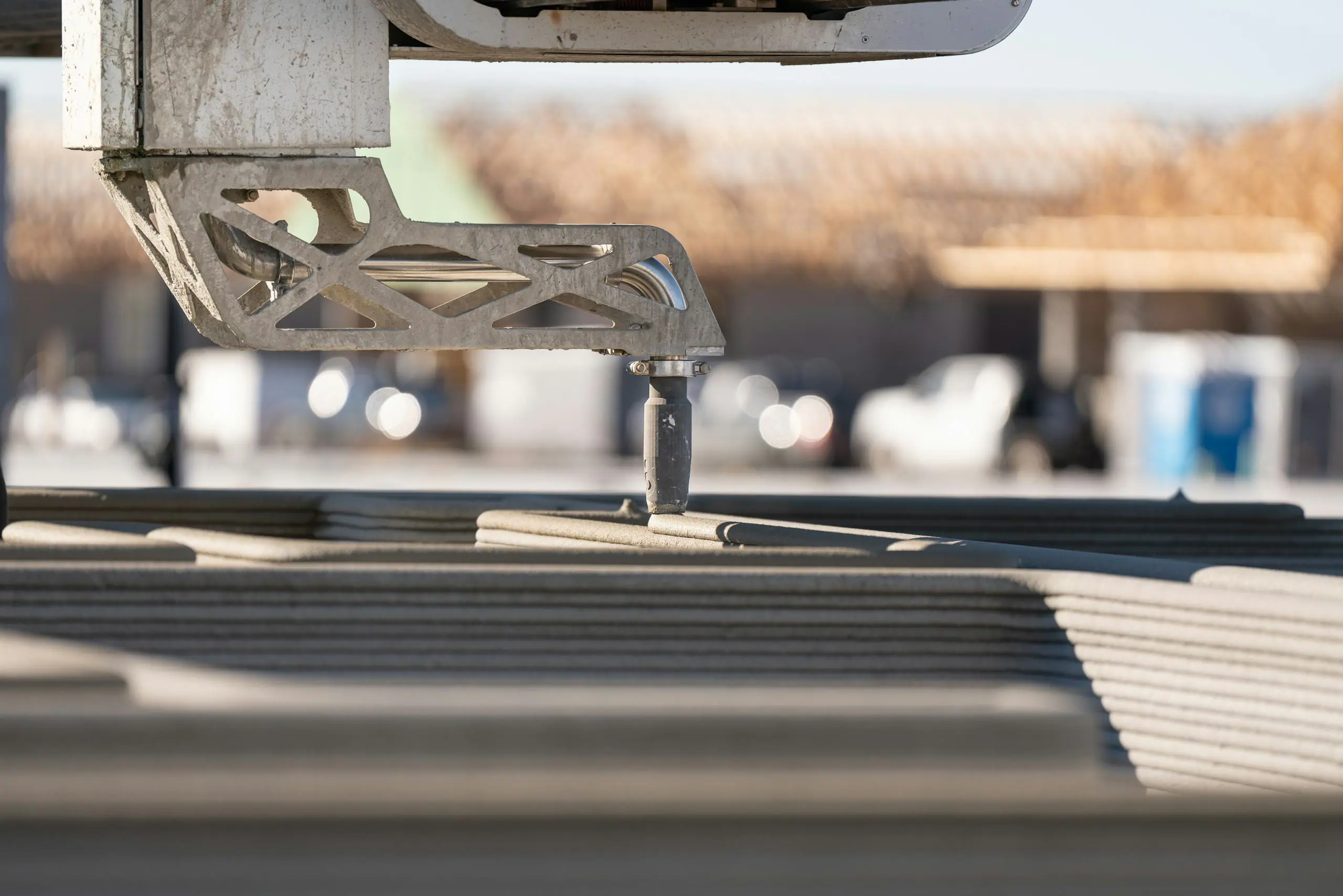 Robotic 3D printing nozzle extruding layered concrete panels for automated construction