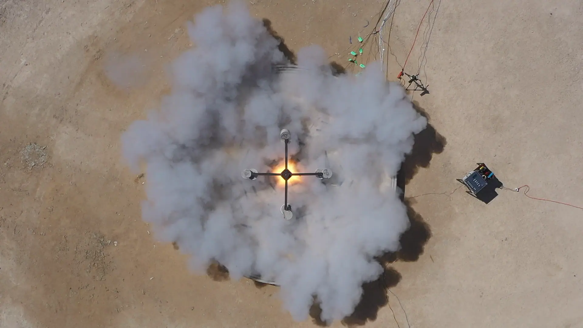 Overhead view of four‑arm robotic 3D‑printing rig emitting flame and smoke during on‑site materials testing