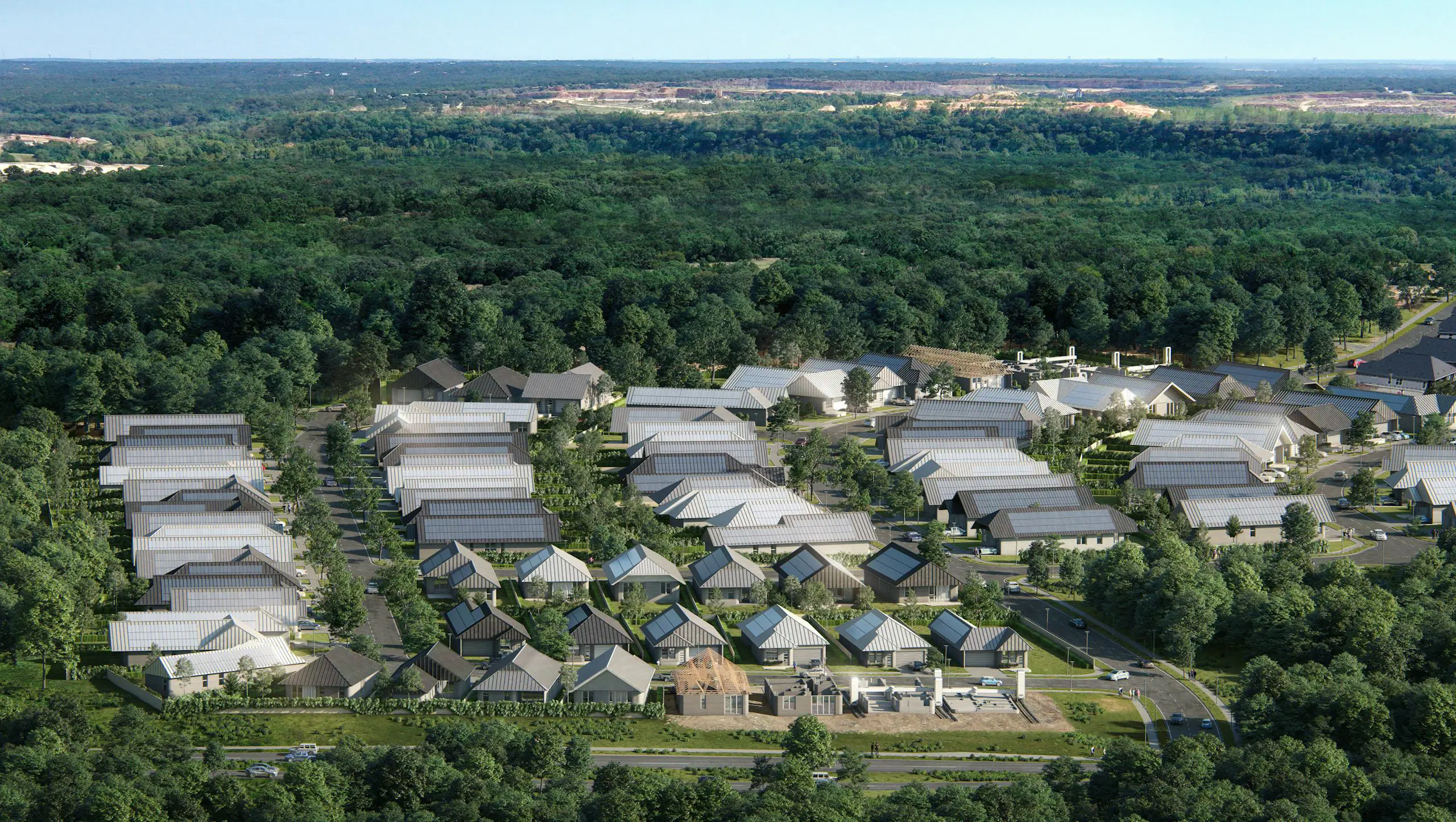 Aerial view of tree-lined neighborhood with modern homes, several under construction, showing design-build housing