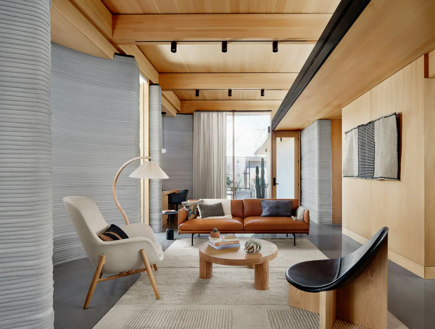 Living room with ribbed 3D-printed walls, timber ceiling and leather sofa illustrating tech-driven design-build interior