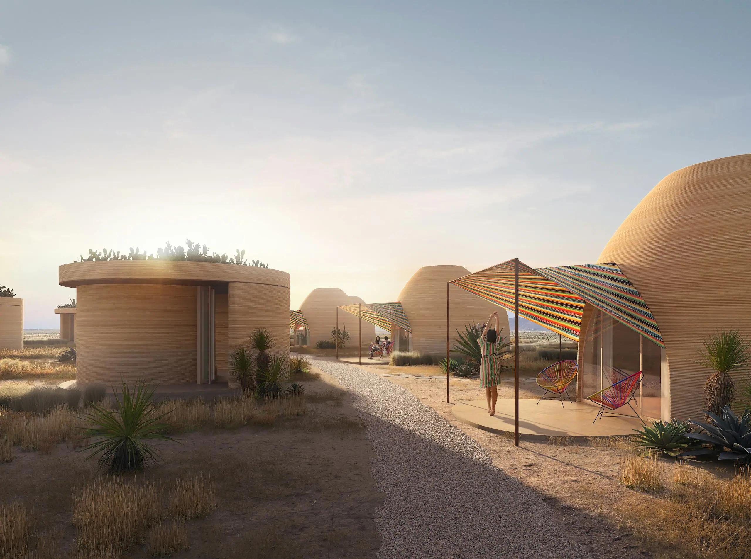 Circular 3D-printed homes with rooftop planters and striped shade canopies in a desert residential community