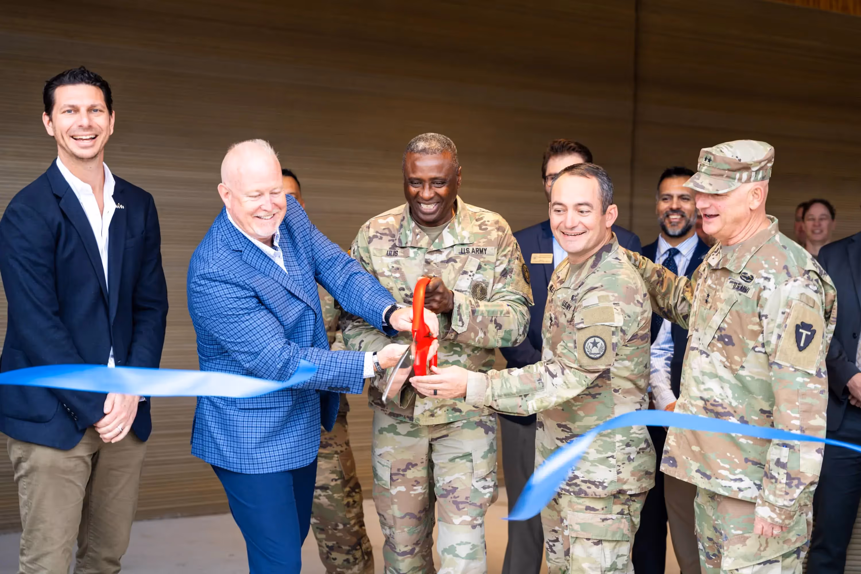 Icon Build executives and U.S. Army officers cutting a blue ribbon together at a facility opening ceremony