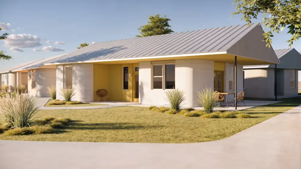Single-story modern 3D-printed home with curved walls, metal roof and front porch in landscaped residential community