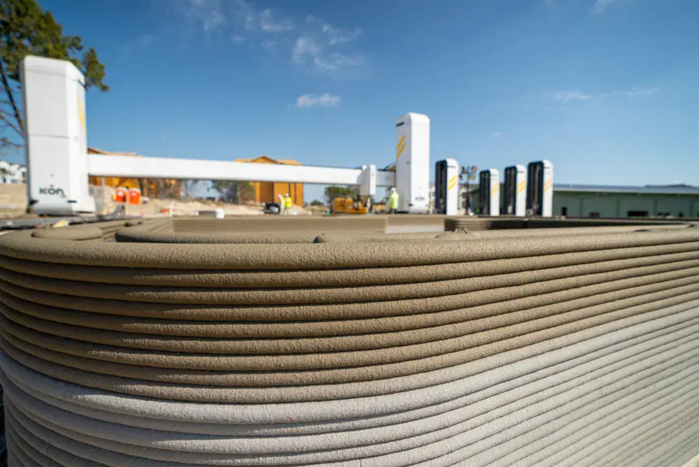 Layered concrete wall from 3D-printing with robotic gantry printer and workers on a construction site