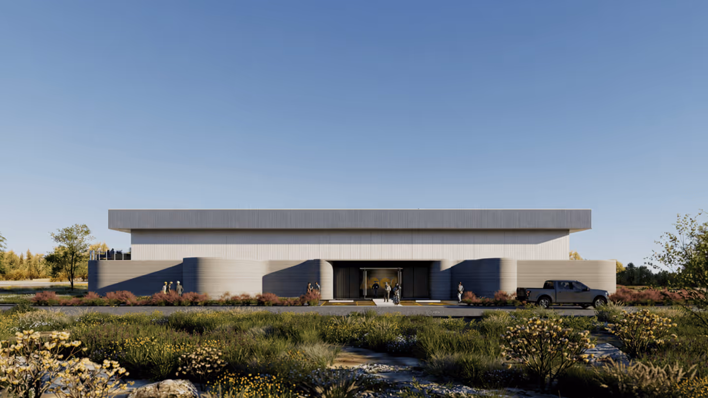 Modern flat-roof building with curved concrete facade, landscaped foreground, people and pickup truck