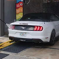 White Ford Mustang convertible parked inside a garage with service equipment around.