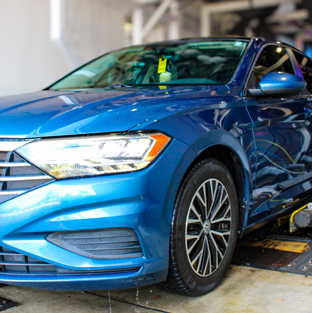 Blue Volkswagen Jetta inside the Rising Tide Coral Springs wash tunnel