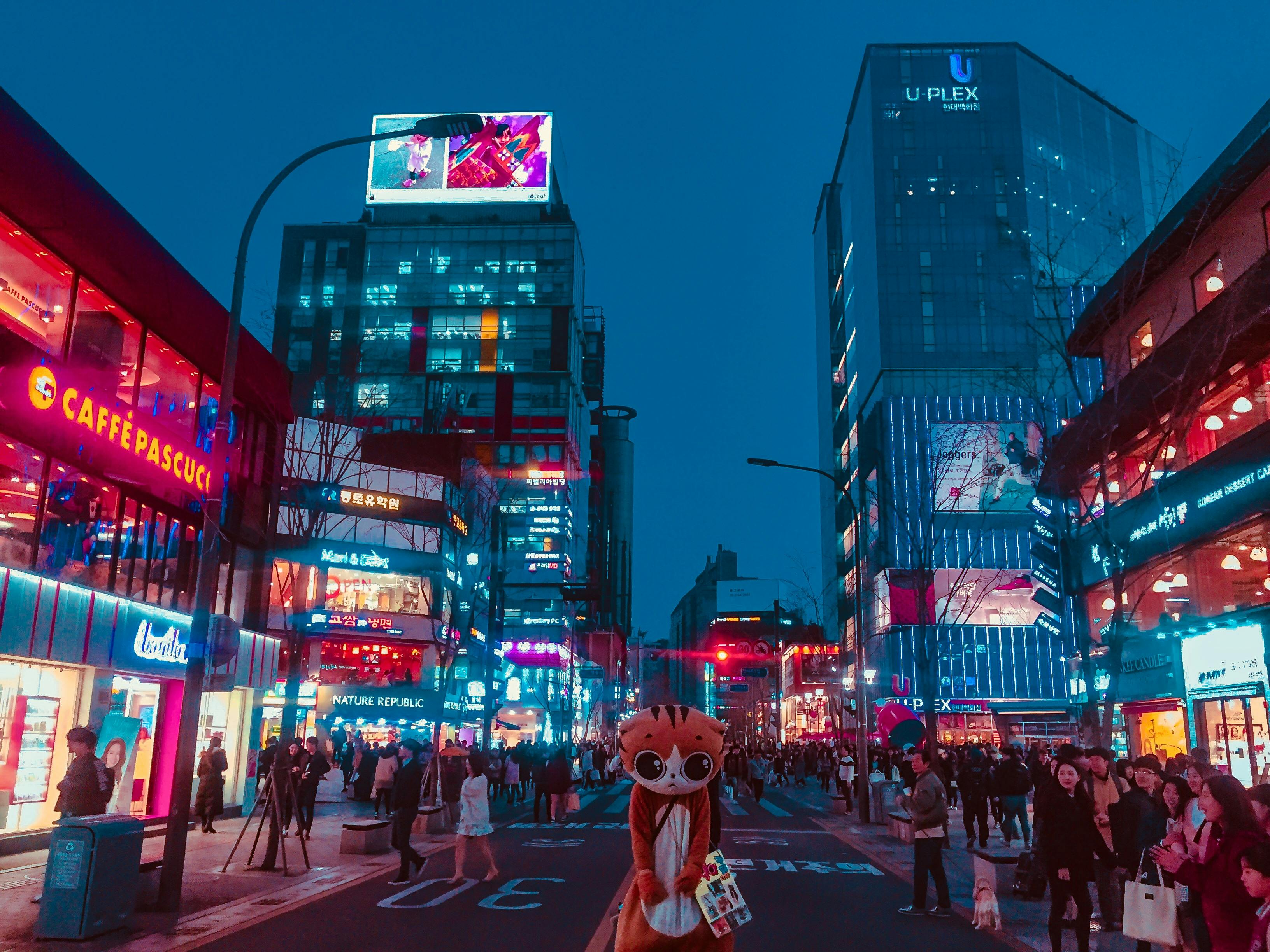 A street in Hongdae, Seoul at night filled with shoppers.