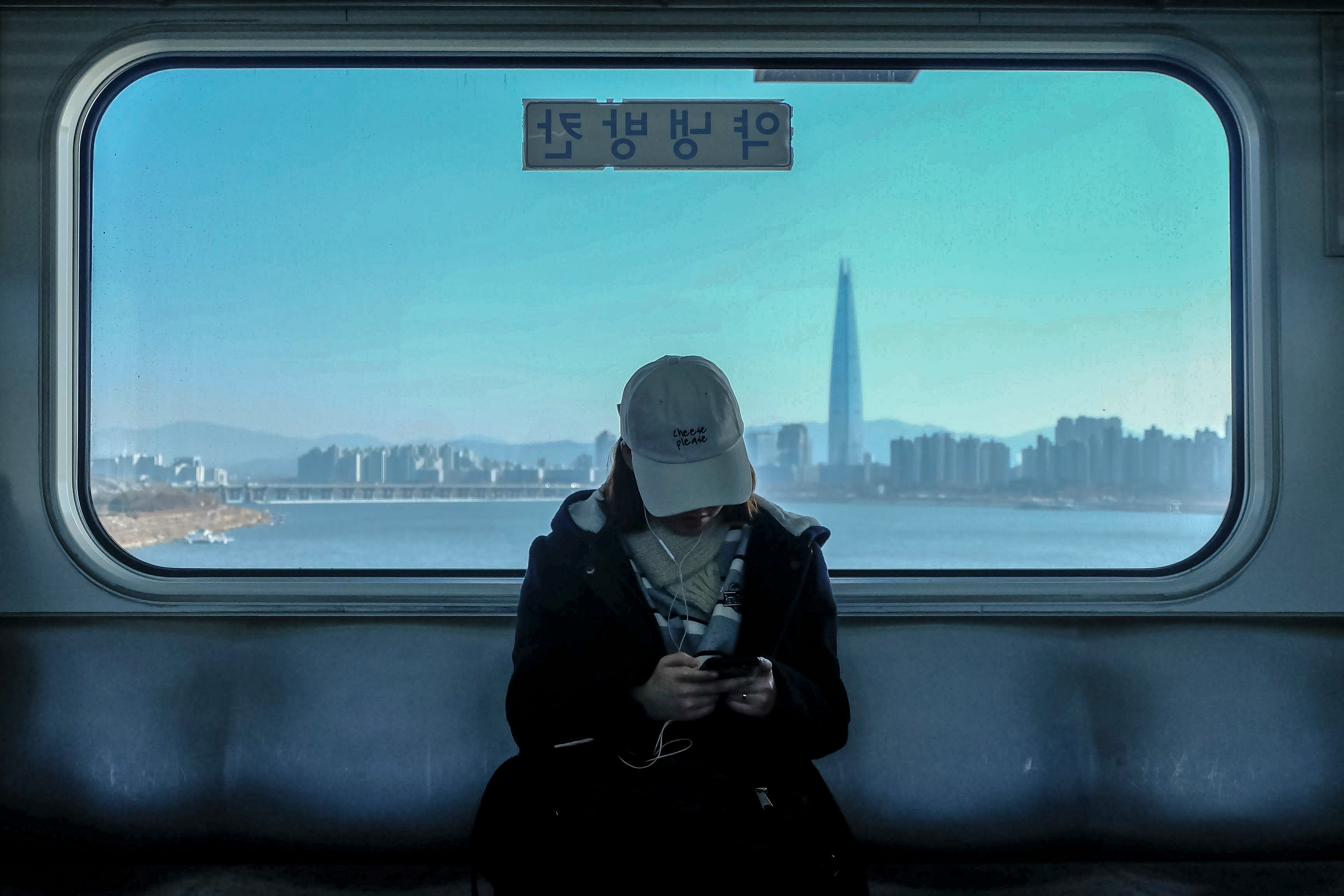 A woman uses the Seoul subway, with Lotte Tower and the Han River in the background.