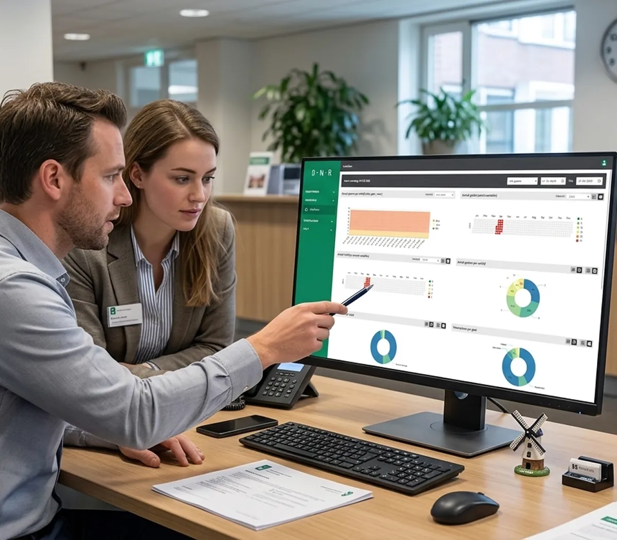 Twee gemeente-medewerkers kijken naar een computerscherm met daarop de grafieken vanuit het Digitaal Nachtregister.