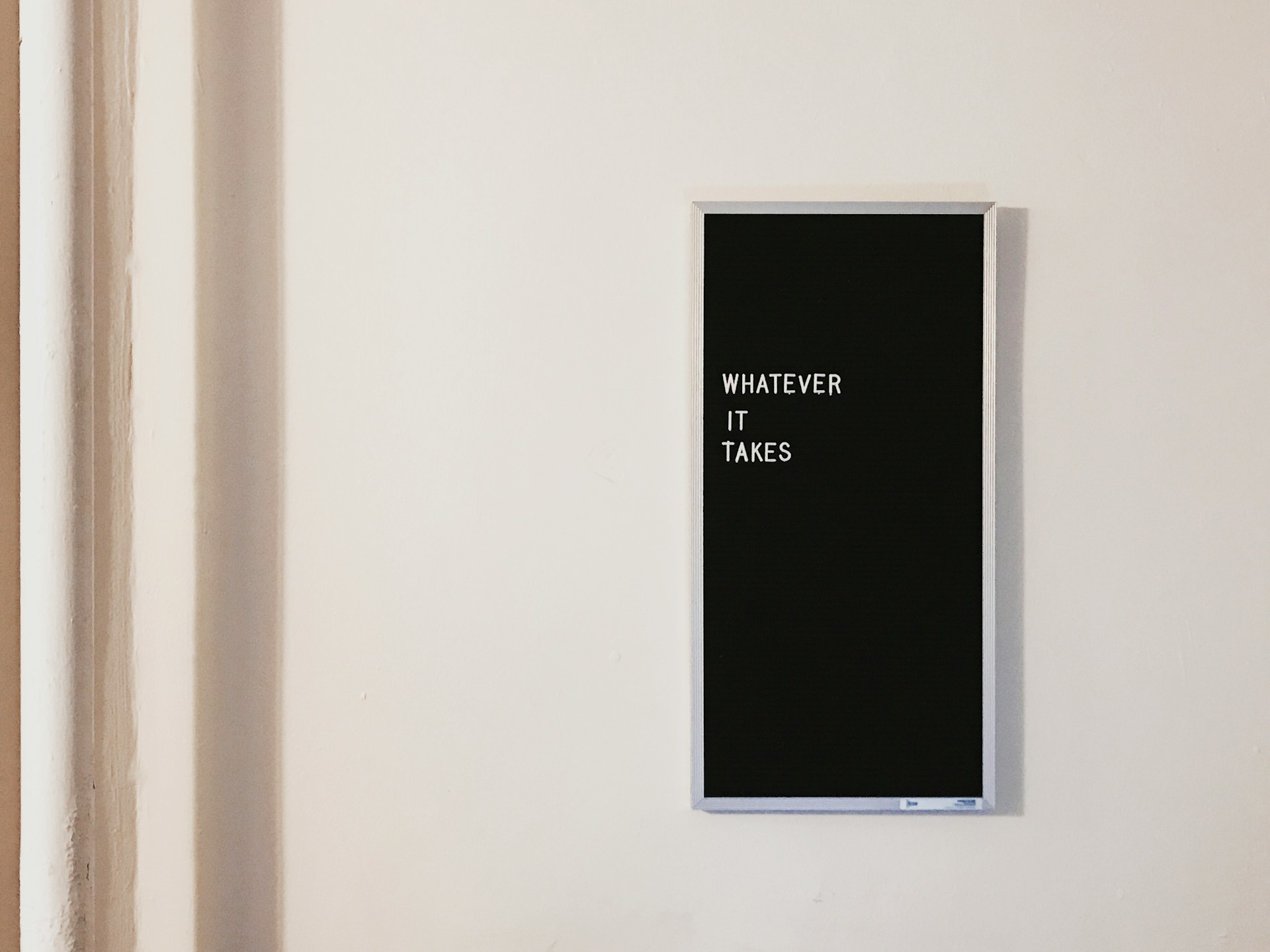 ein schild hängt an einer weißen Wand mit der Aufschrift whatever it takes
