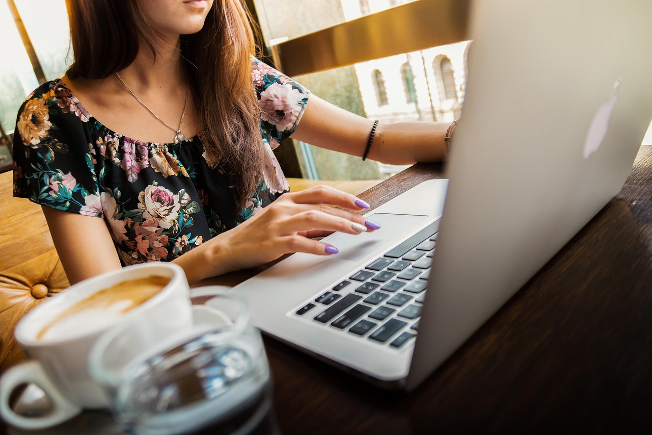 Frau sitzt am Computer mit einem Kaffe