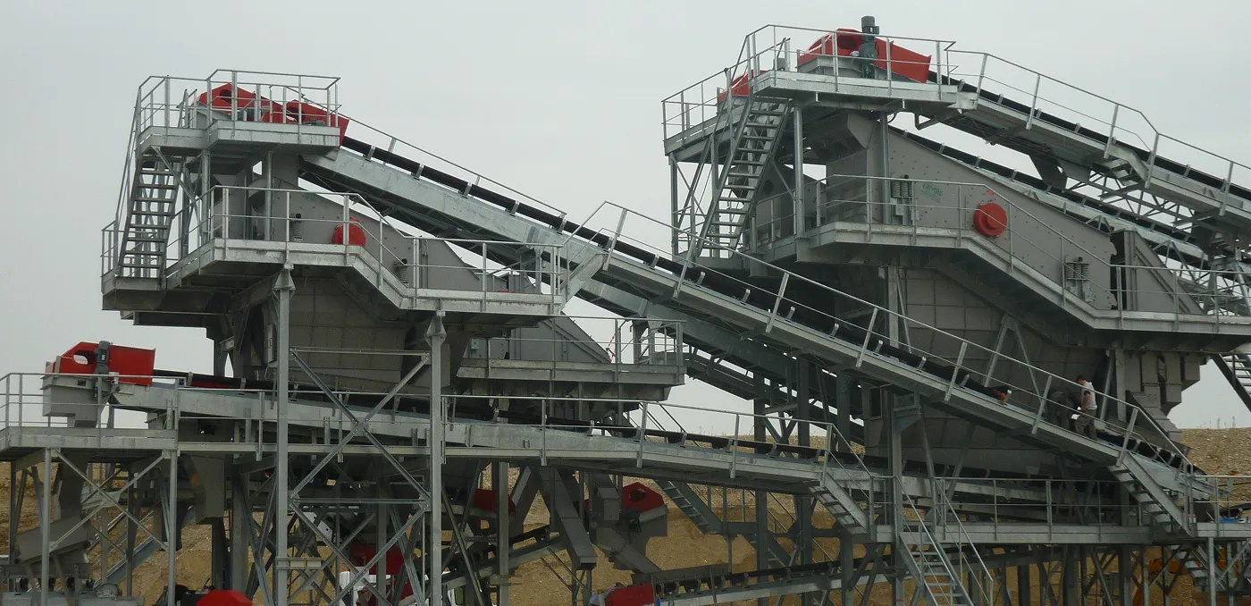 Grand système de convoyage industriel avec plateformes métalliques et escaliers sur un site minier ou de construction.
