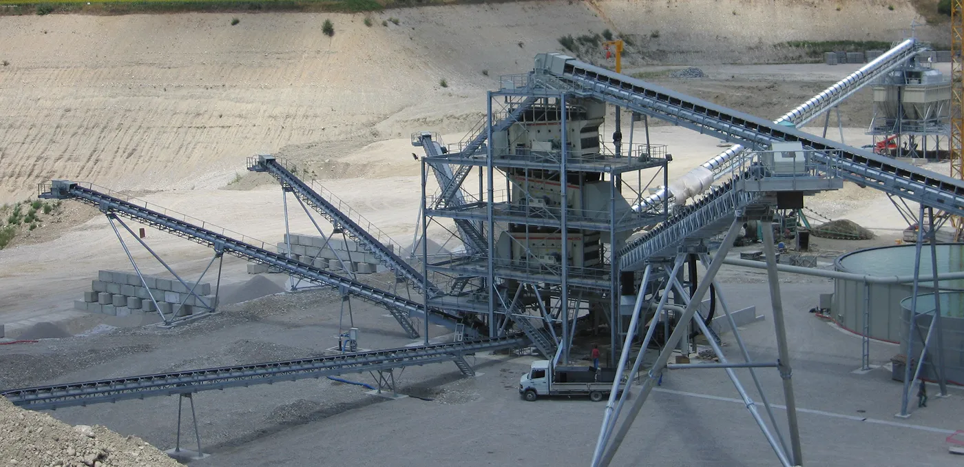 Site de carrière industrielle avec des bandes transporteuses et des machines pour le traitement des matériaux.