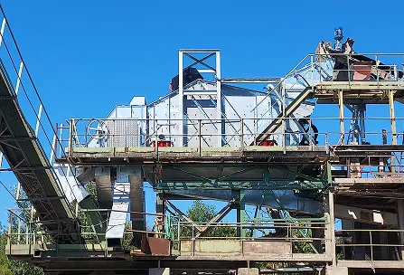 Structure métallique industrielle avec des bandes transporteuses et des garde-corps sous un ciel bleu dégagé.