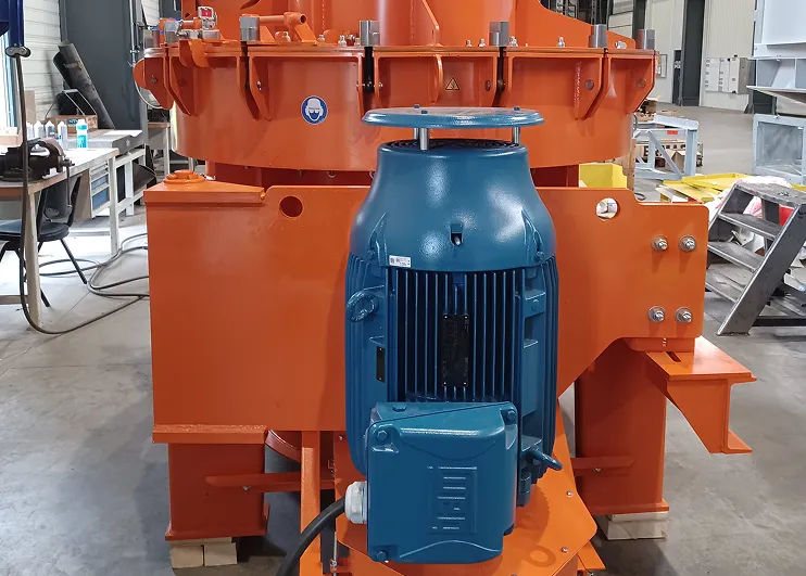 Moteur industriel bleu fixé à une grande machine orange dans un atelier avec des sols en béton.