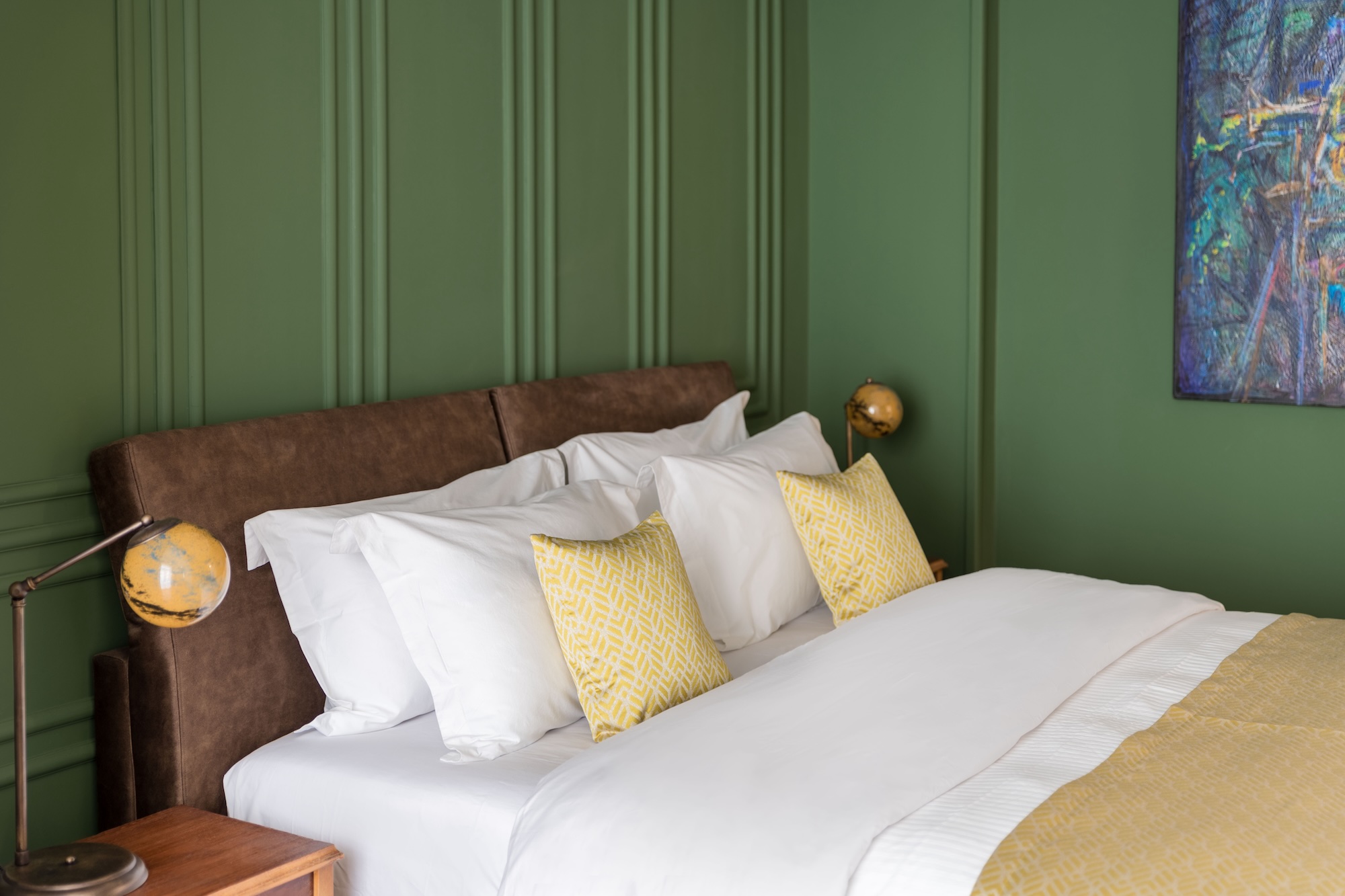 Double bed with green feature wall at The Hive apartment in Kypseli Athens