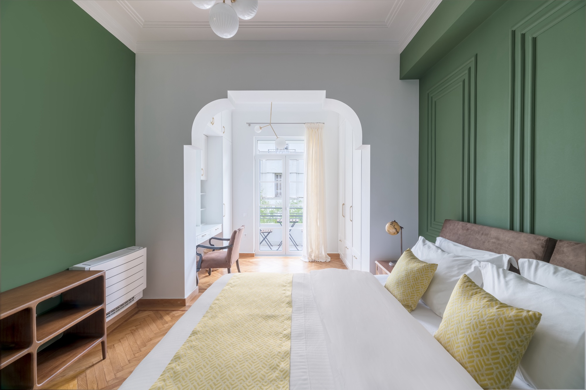 Spacious bedroom with green feature wall at The Hive apartment in Kypseli Athens
