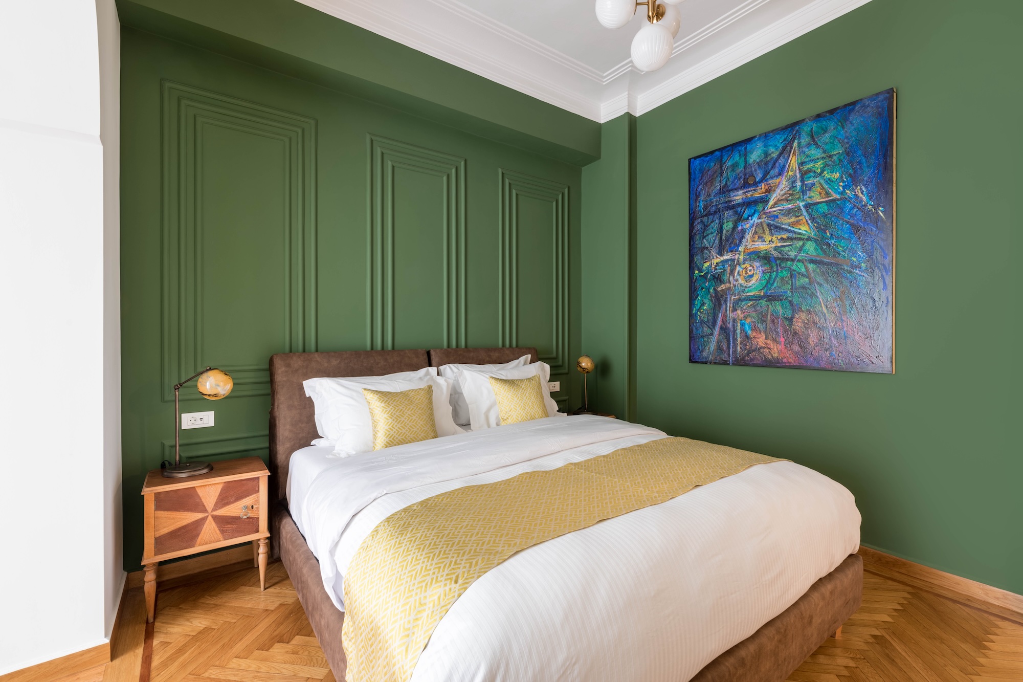 Double bedroom with green wall and artwork at The Hive apartment in Kypseli Athens