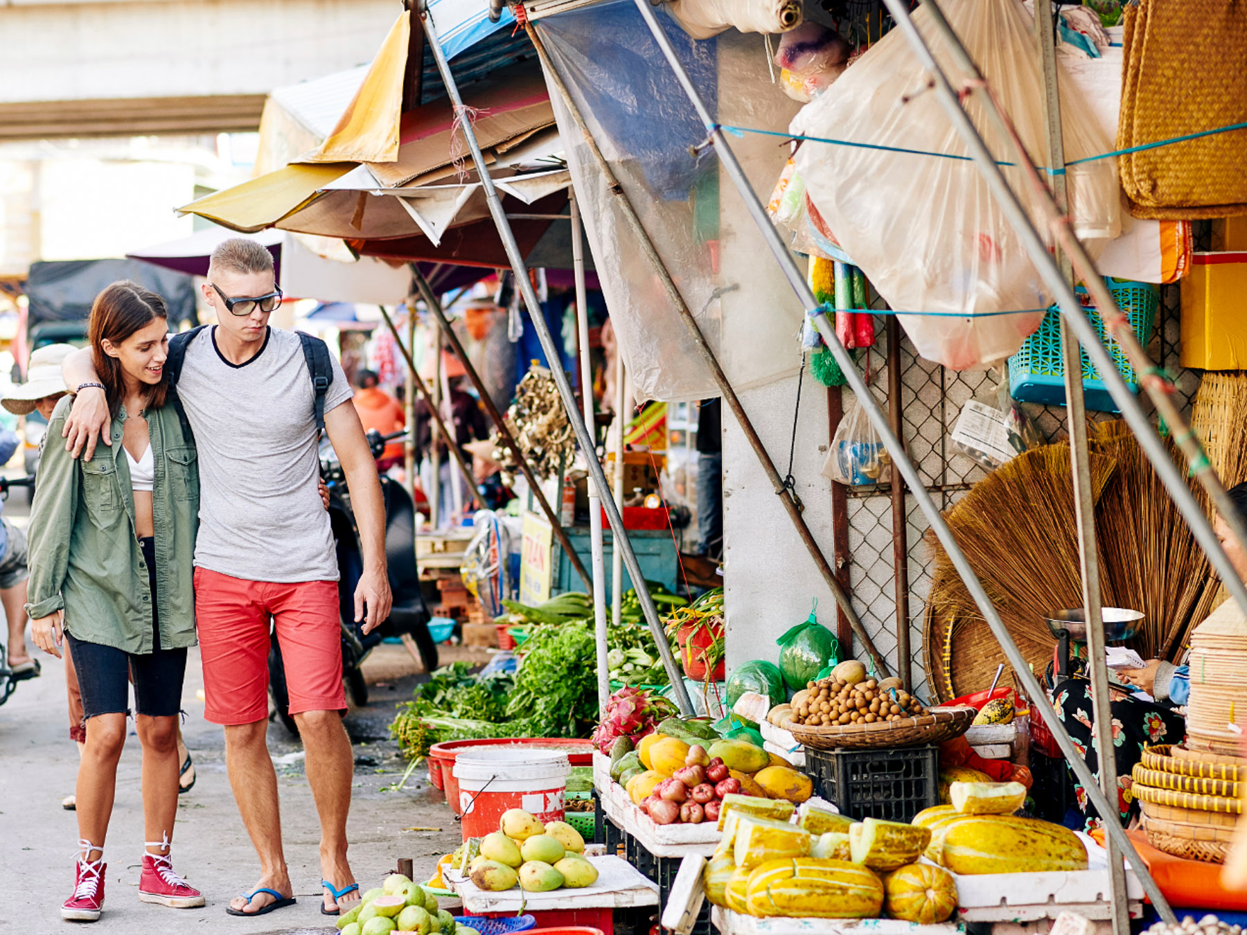 Young couple strolling through an Athens market with vegetables and woven goods