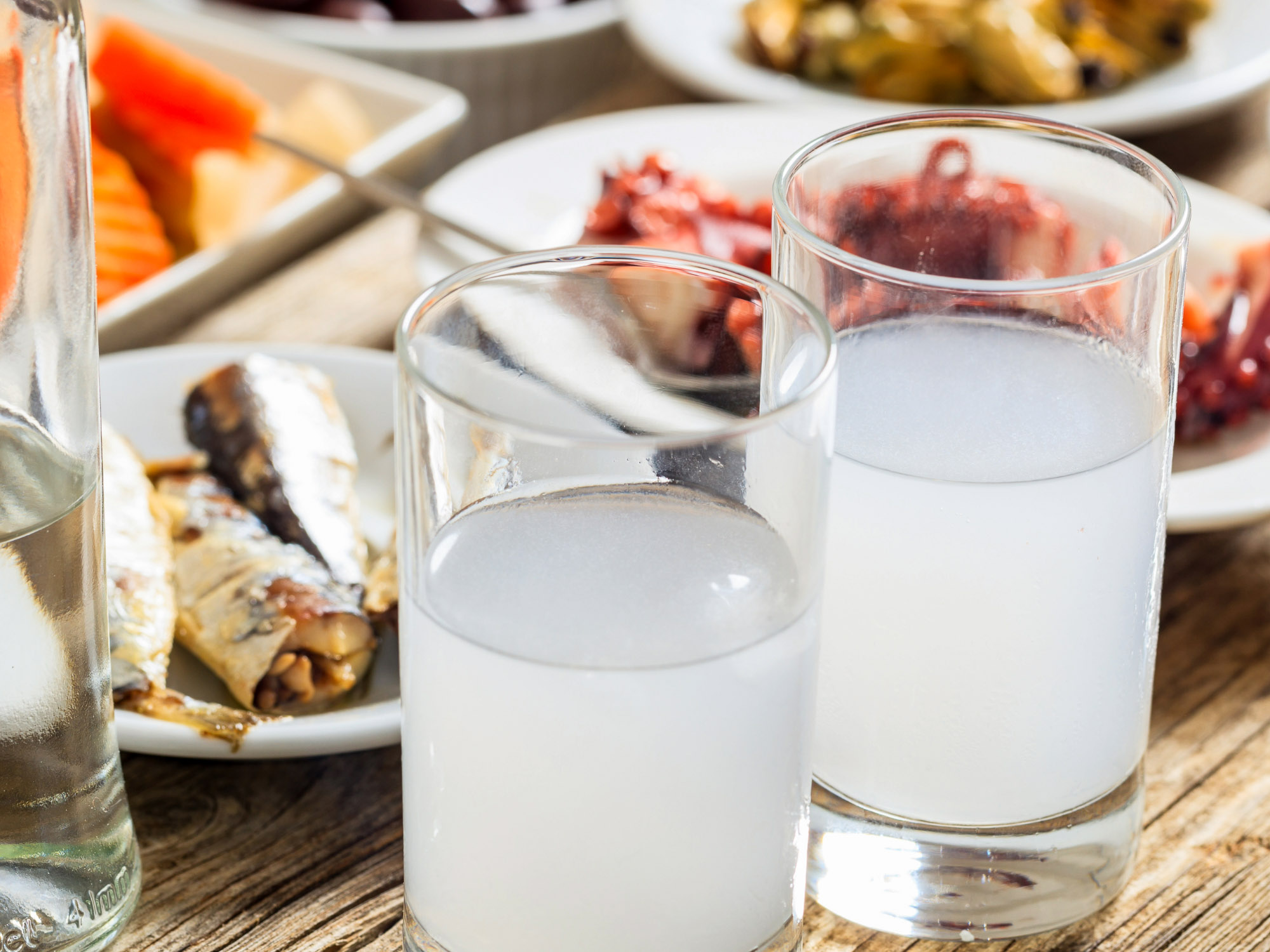 Meze and ouzo on a wooden table, evoking Lycabettus Athens old stories of shared food and parea