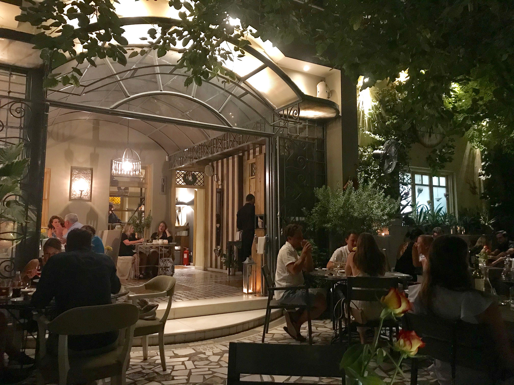 Guests dining in a courtyard restaurant at night in Metaxourgeio, Athens