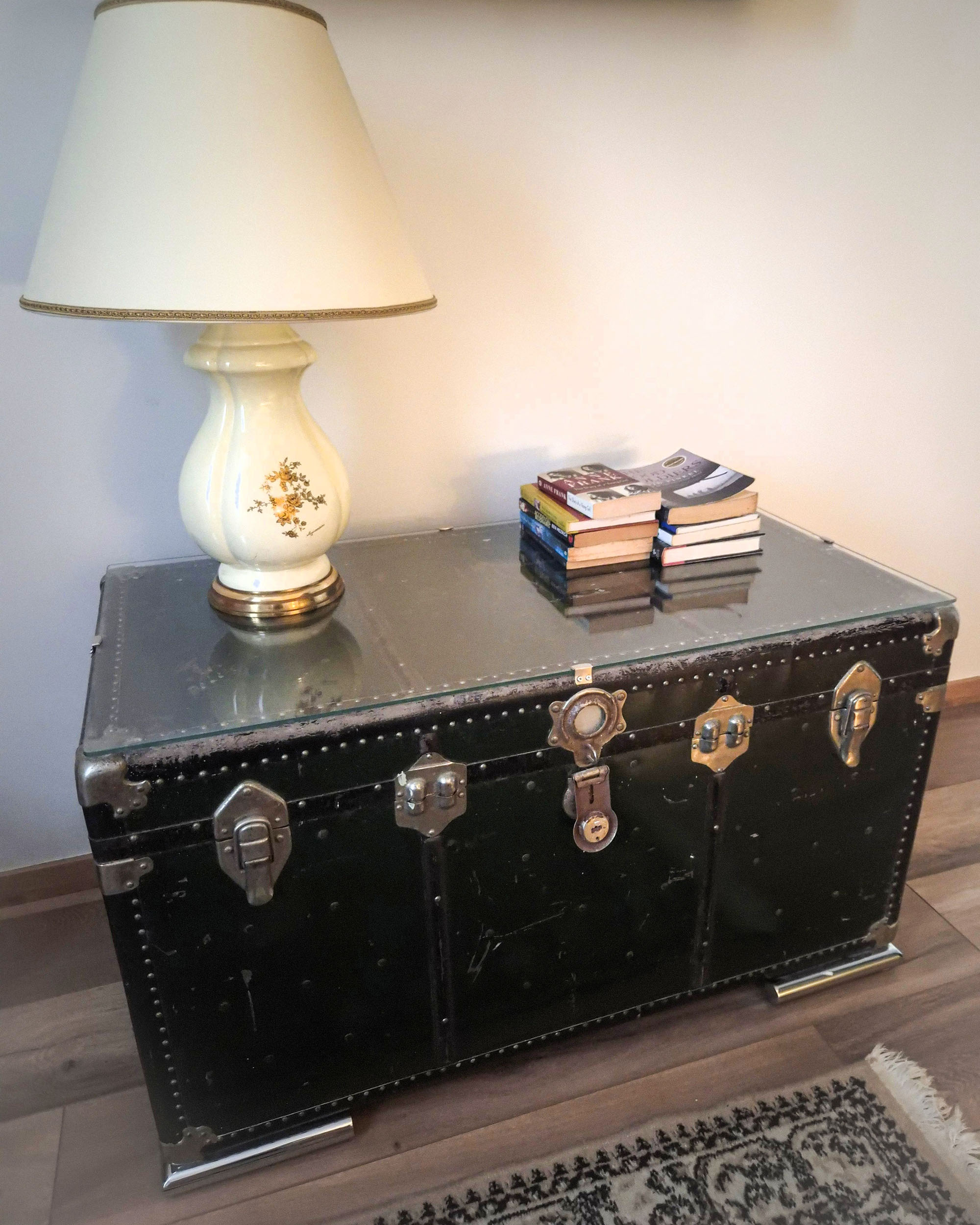 Black vintage travel trunk with books and a table lamp at Silk House boutique accommodation in Metaxourgeio.