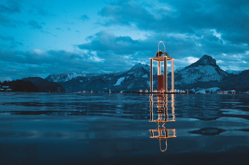 Friedenslicht-Laterne im Wolfgangsee vor verschneiten Bergen