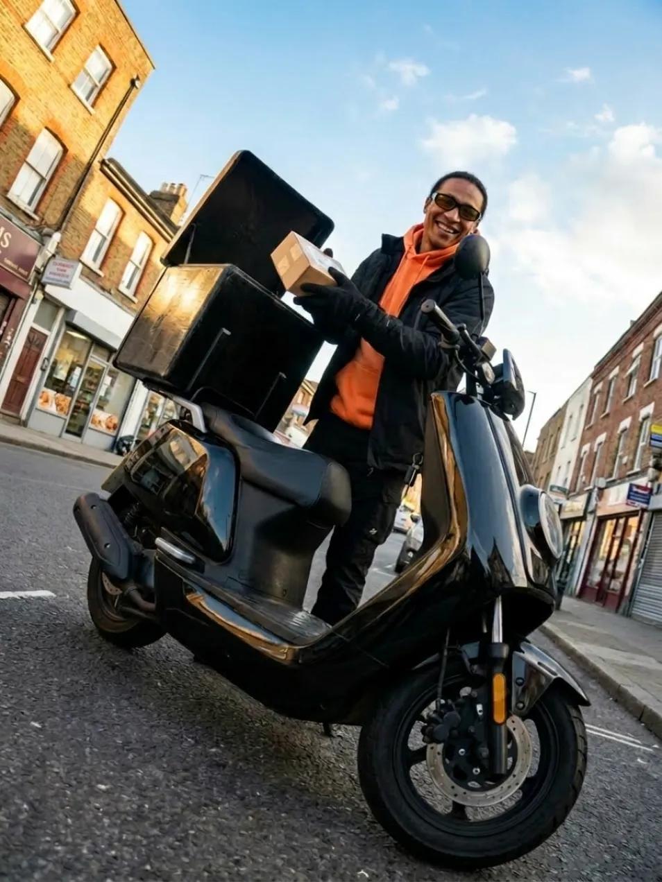Relay courier on a scooter in an East London street at golden hour