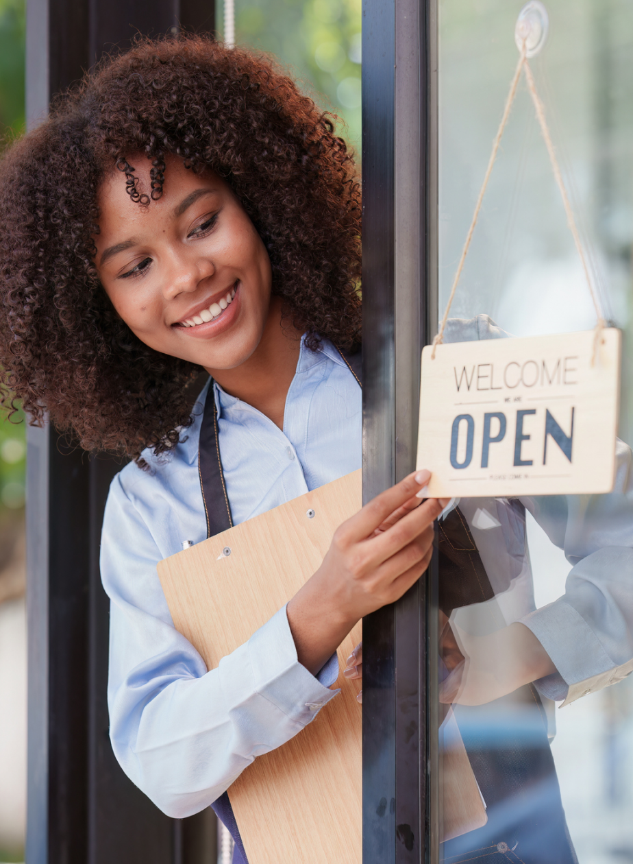 A happy entrepreneur opening her shop after getting her small business books set up correctly.