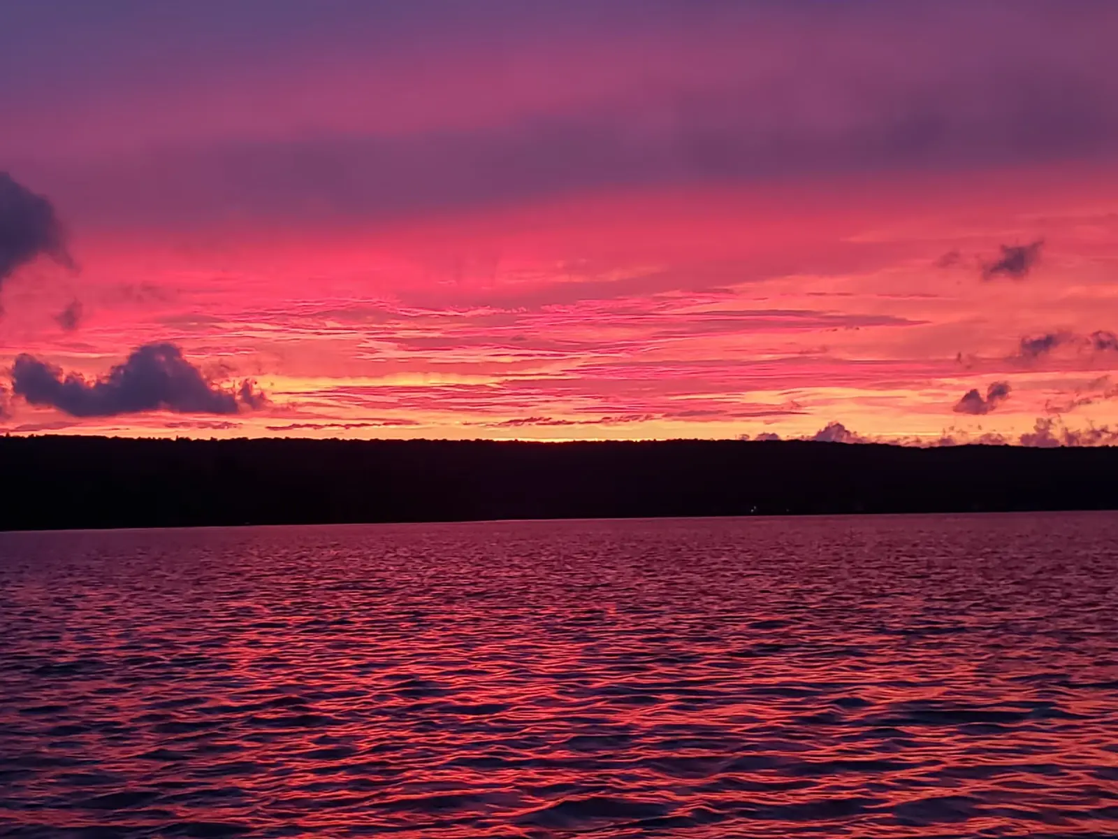 Vivid pink and red sunset over a calm lake.