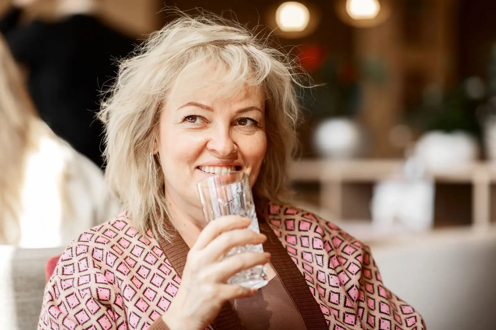 Smiling woman drinking a glass of water.