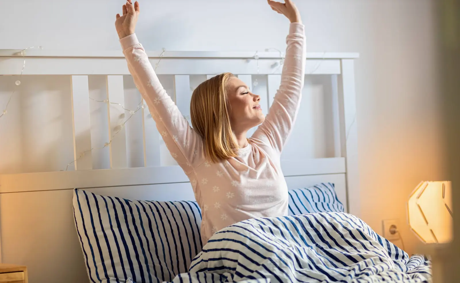 Woman stretching happily as she wakes up in bed.