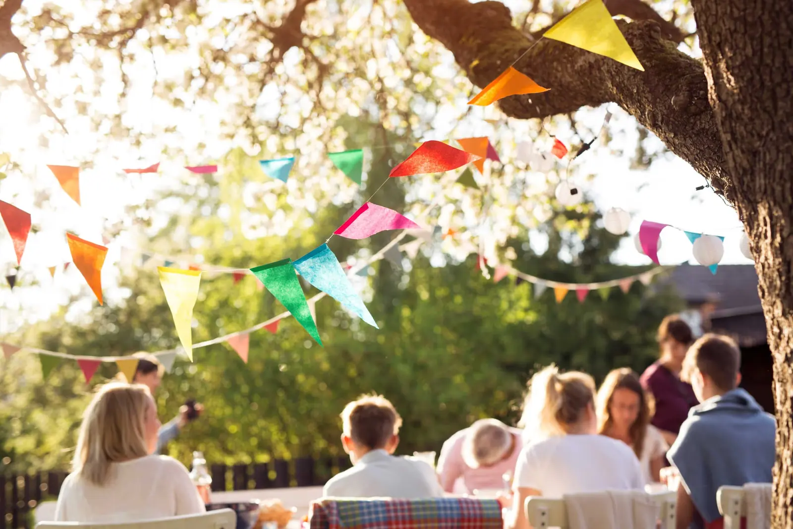 Friends at an outdoor summer garden party under colourful bunting.