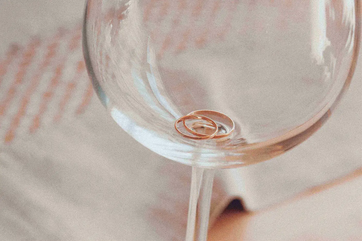 Wedding rings lying in the bottom of an empty wine glass.