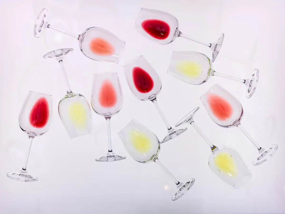 Empty wine glasses with traces of red, rose and white wine scattered on a white surface.